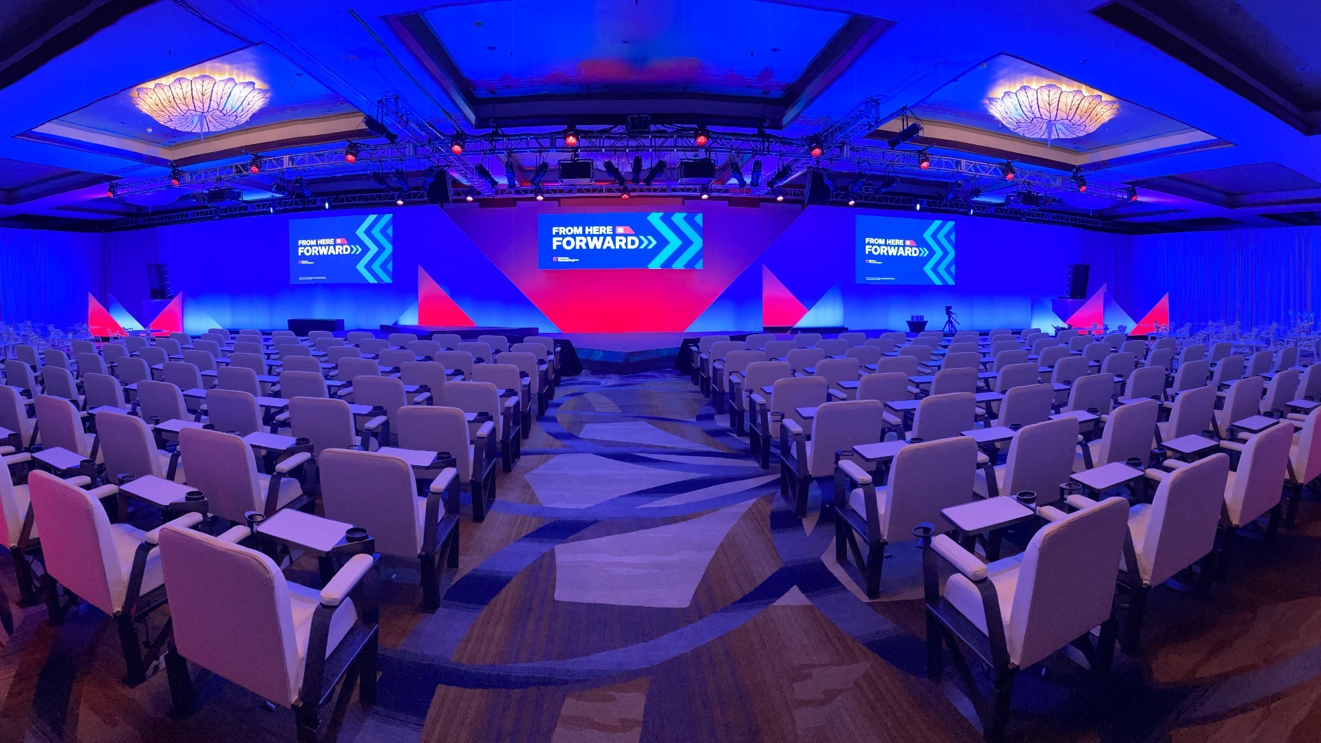 A ThirdEye-produced corporate event room with colorful stage lighting and a wide presentation display.